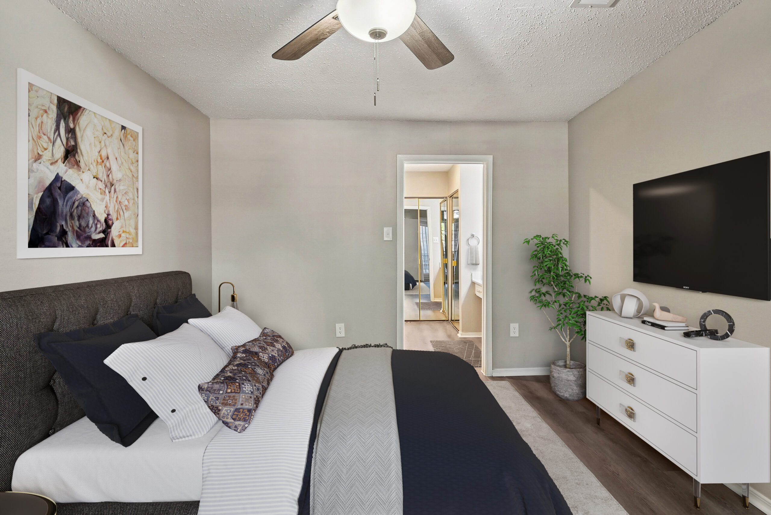 Modern bedroom a Garland Texas apartment, featuring wood-style flooring, contemporary décor, and ensuite bathroom access.