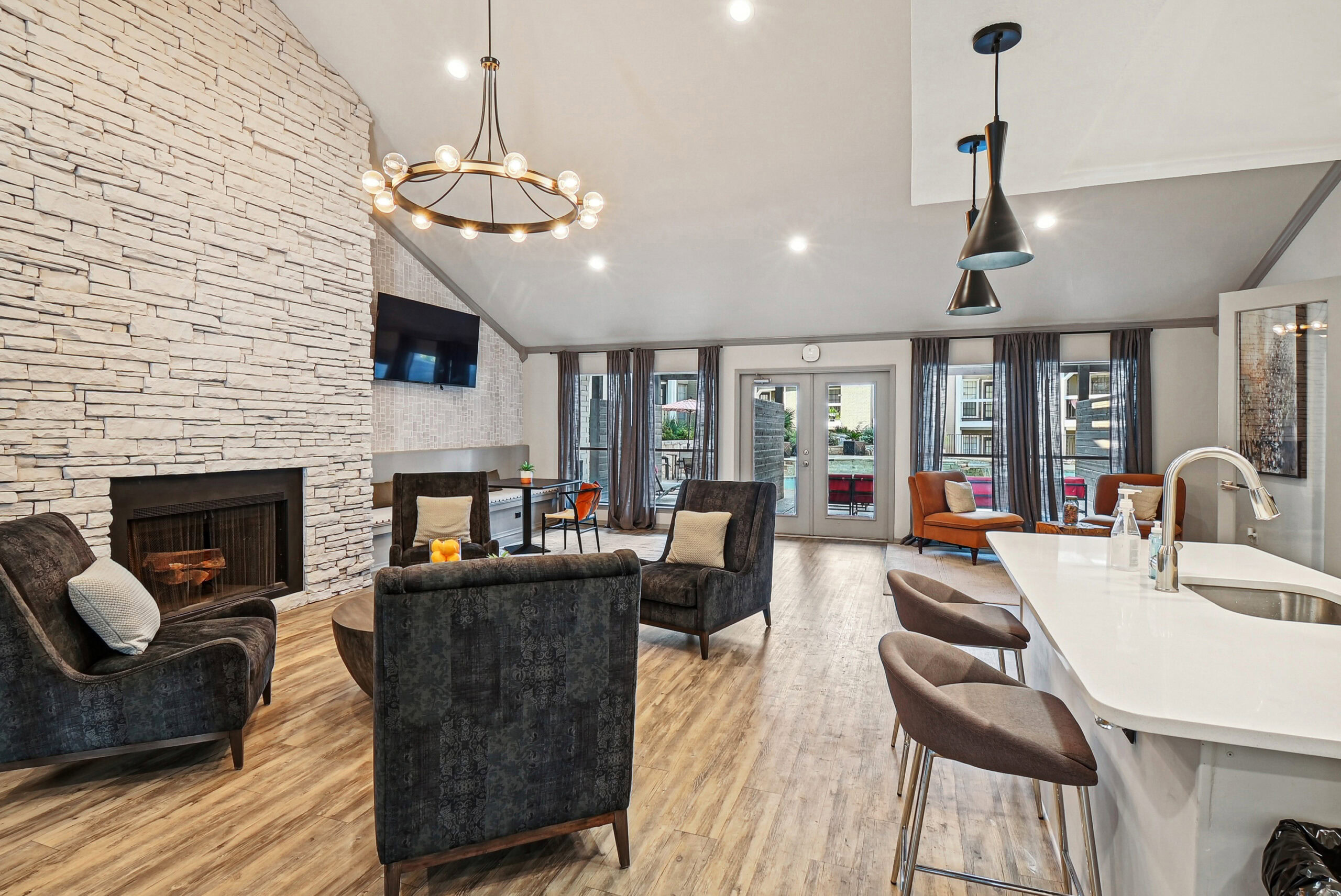 Resident clubhouse at the Arbors of Las Colinas apartment in Garland Texas featuring a modern lounge area, stone fireplace and stylish seating