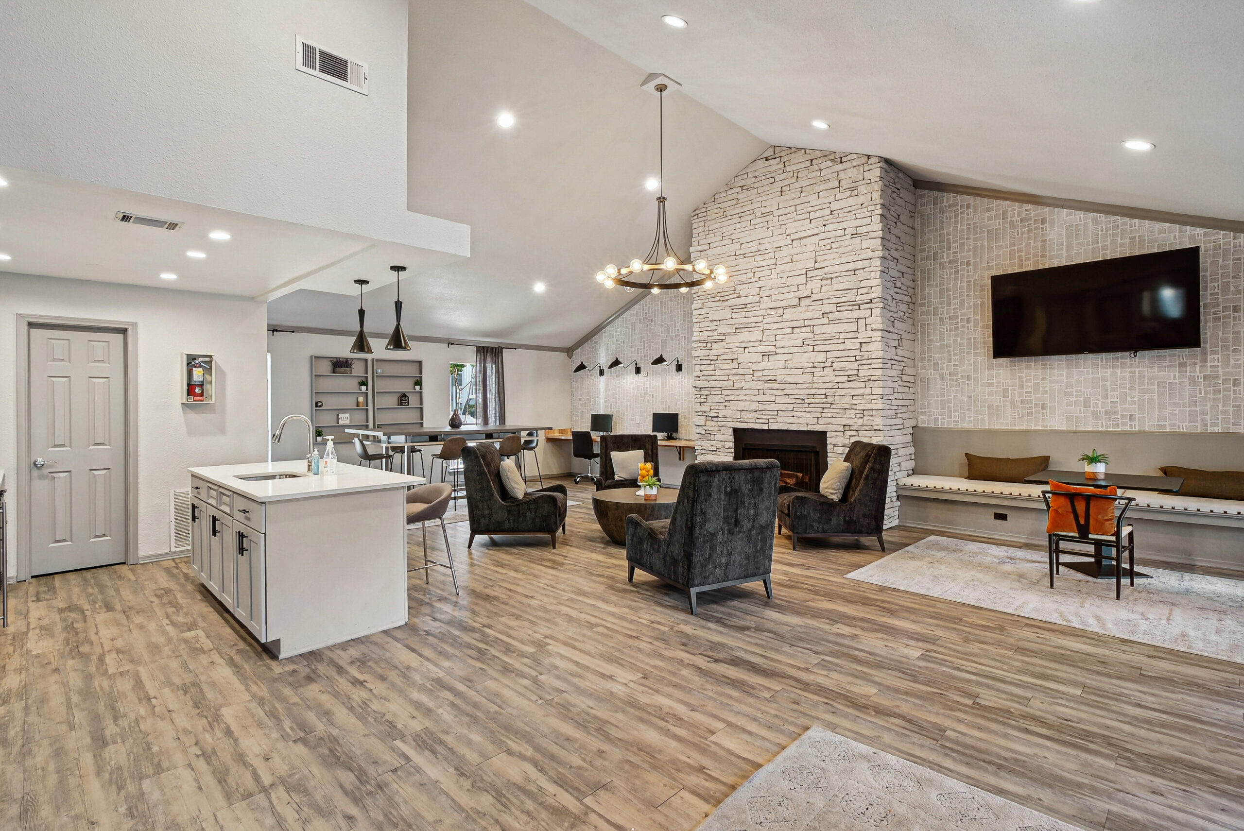 Resident clubhouse at the Arbors of Las Colinas apartment in Garland Texas featuring a modern lounge area, stone fireplace and stylish seating