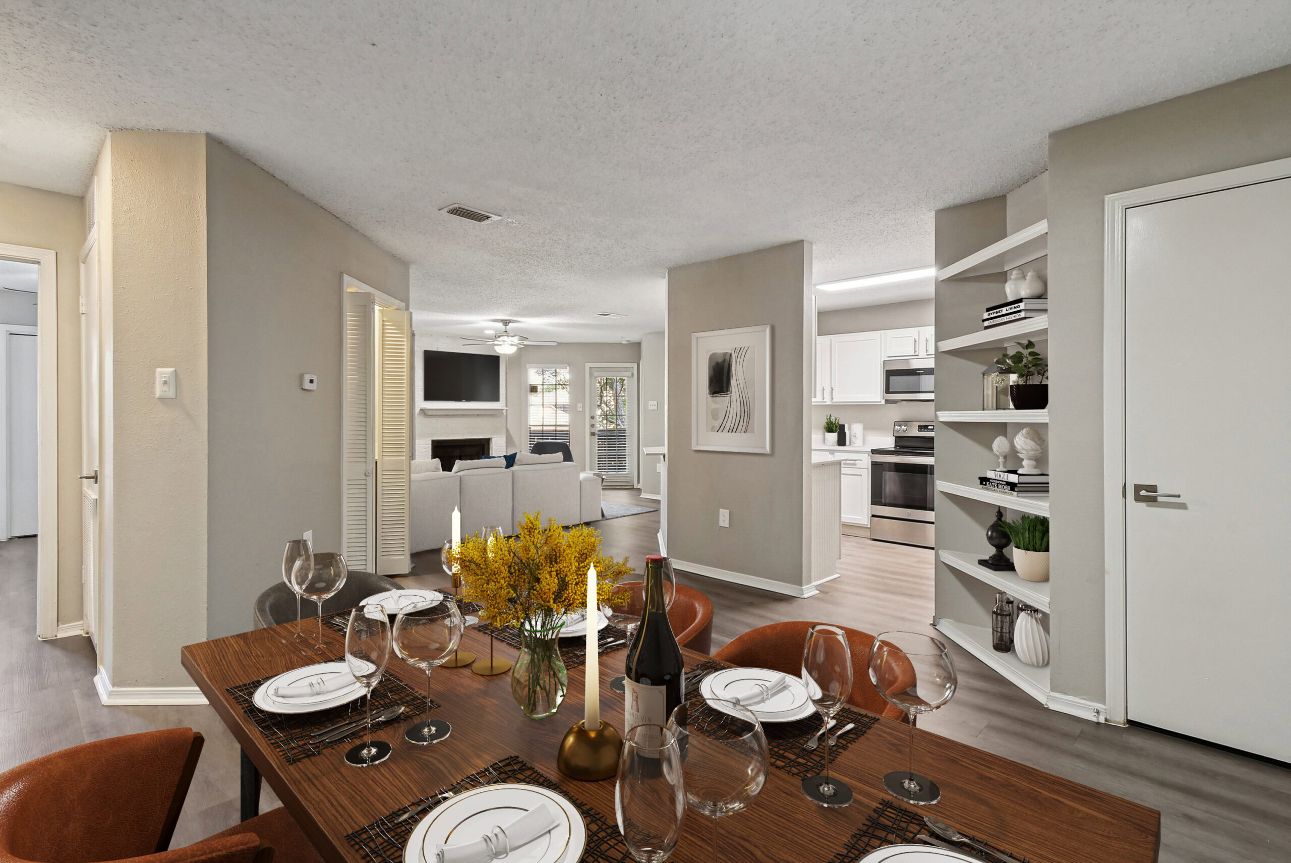 Dining room view inside an apartment in Garland Texas, featuring built-in shelving, wood-style floors, and open access to the living room and kitchen.