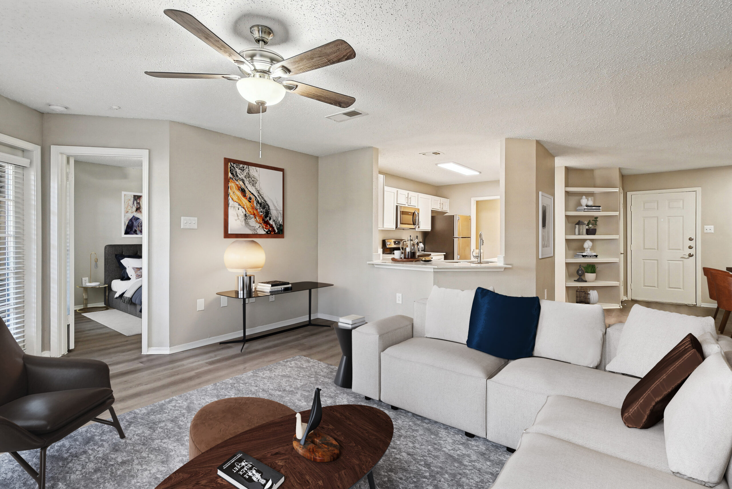 Spacious living room in a Garland Texas apartment, featuring modern furniture, wood-style floors, and a kitchen in the corner