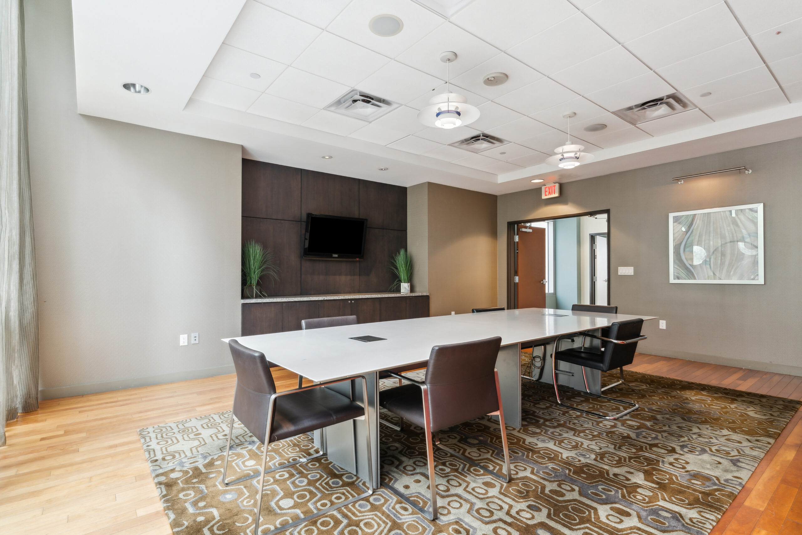 Modern spacious conference room at The Continentals apartments with a large conference table, a geometric rug under it and natural lighting