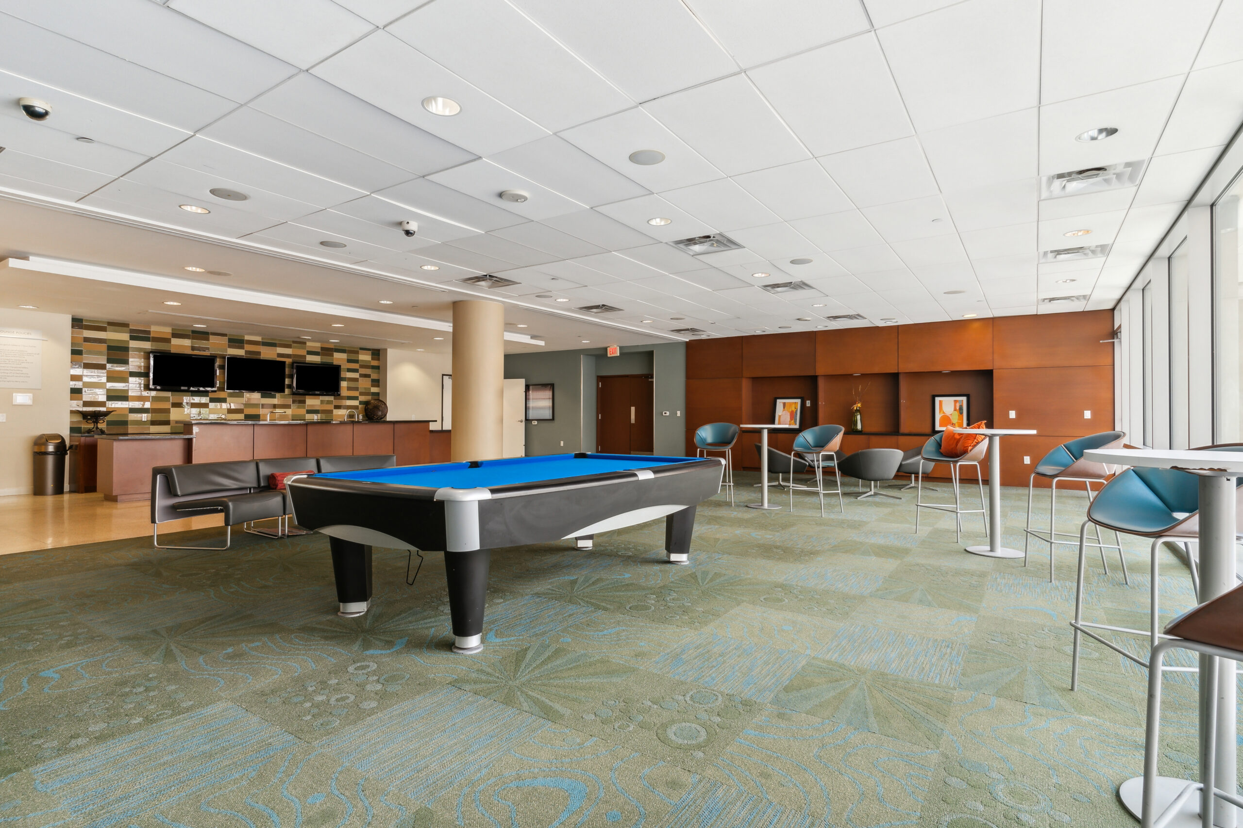 A lounge on the second floor of The Continentals apartment building, featuring high tables, a black and blue pool table, seating and a kitchen area