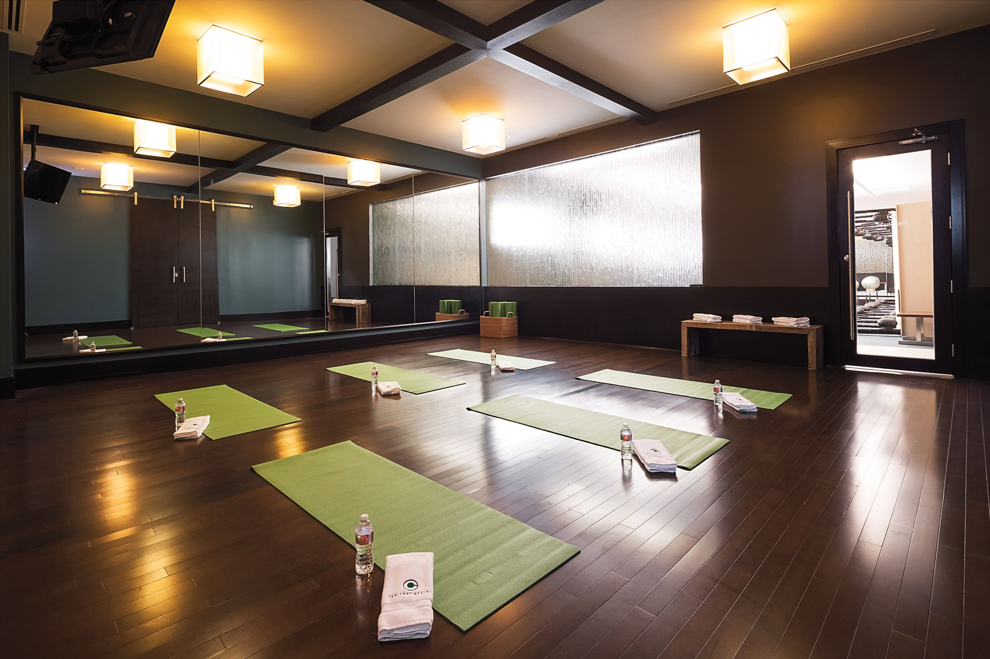 Yoga studio at The Continentals apartments in Dallas, Texas with green yoga matts, branded towels and bottles of water set up for a class