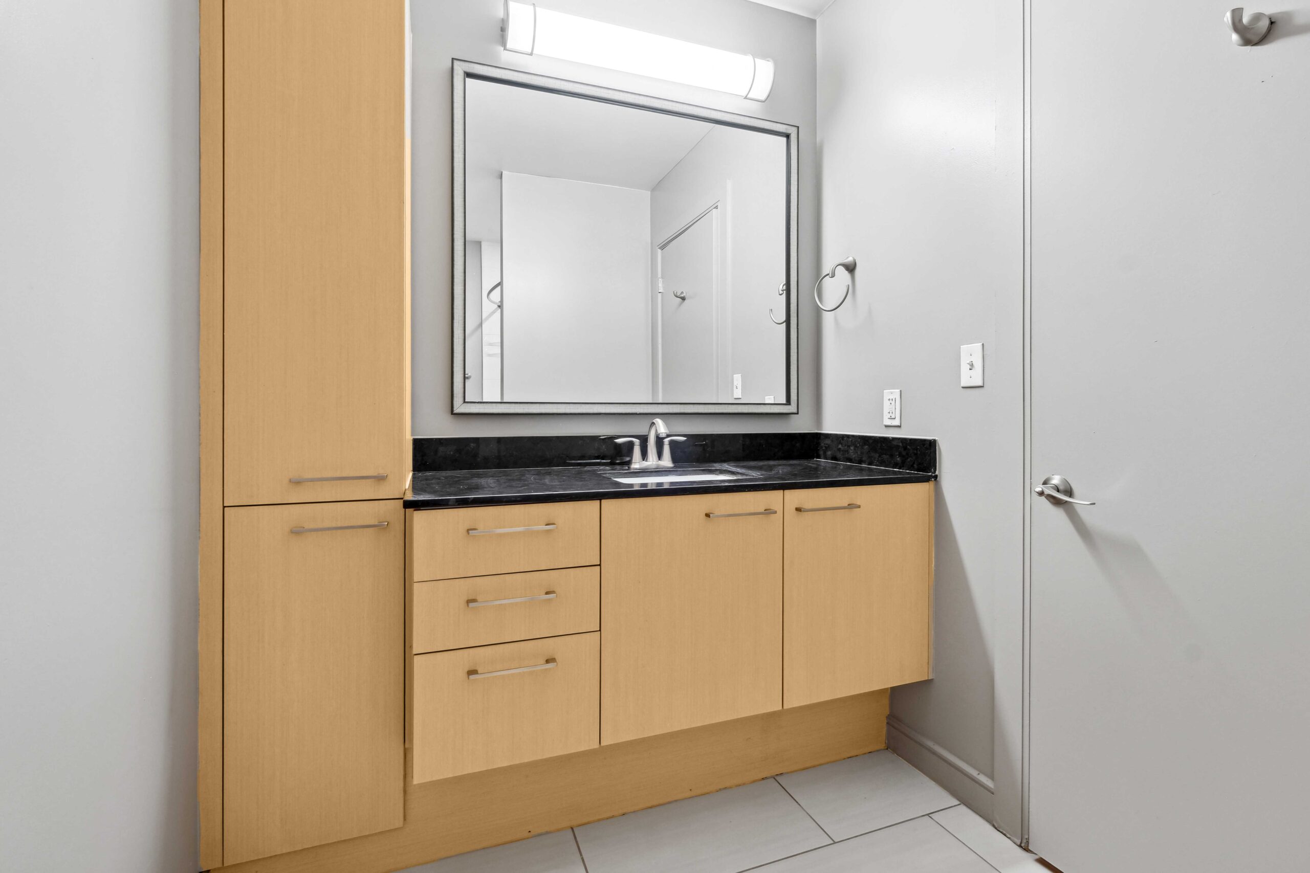 Brightly lit bathroom with a single sink vanity and ample storage space in an apartment at The Continental's housing in Dallas, Texas