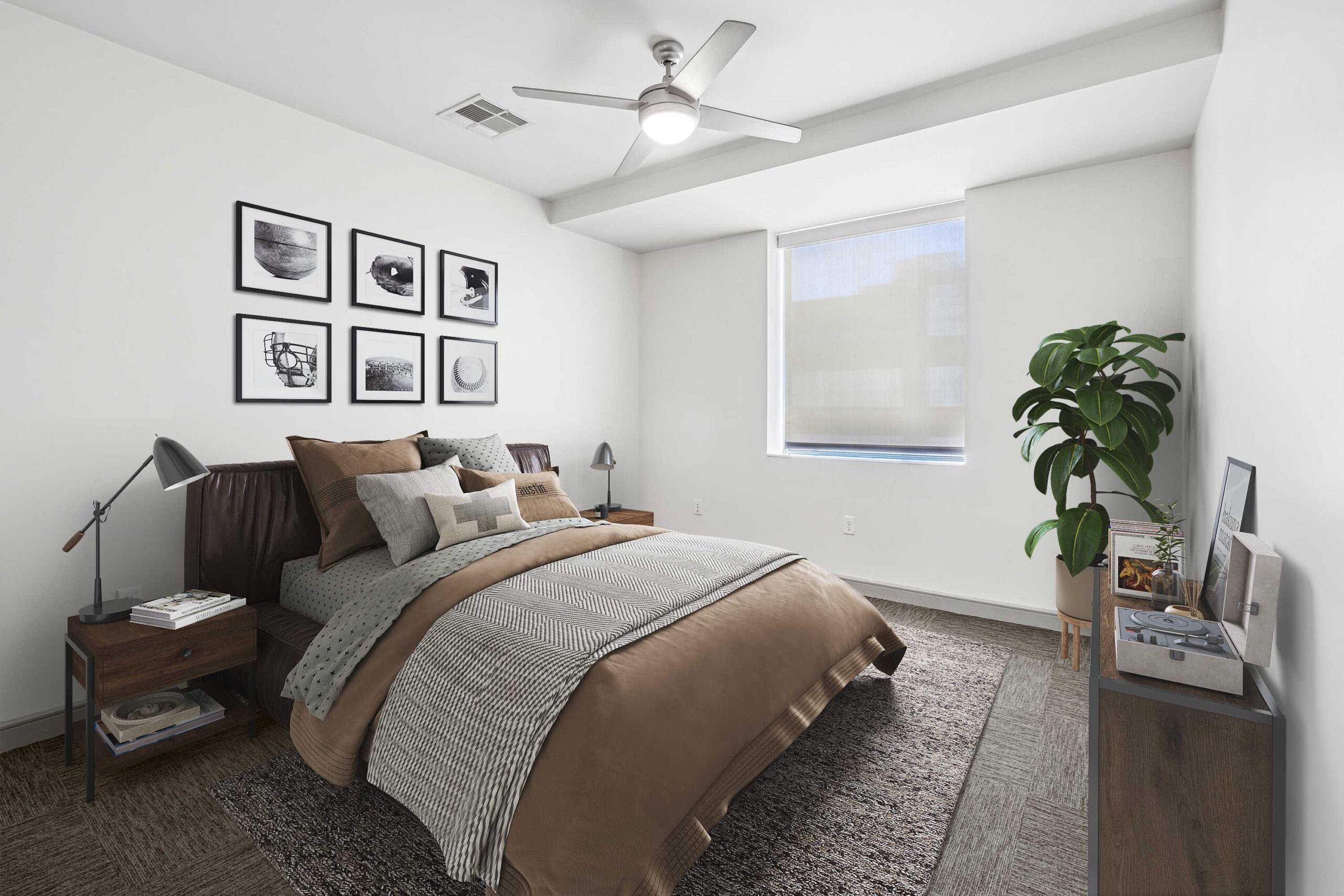 Warm bedroom at The Continental's apartments in Dallas, Texas, with brown furniture and linen, black and white wall art and a rug under the bed