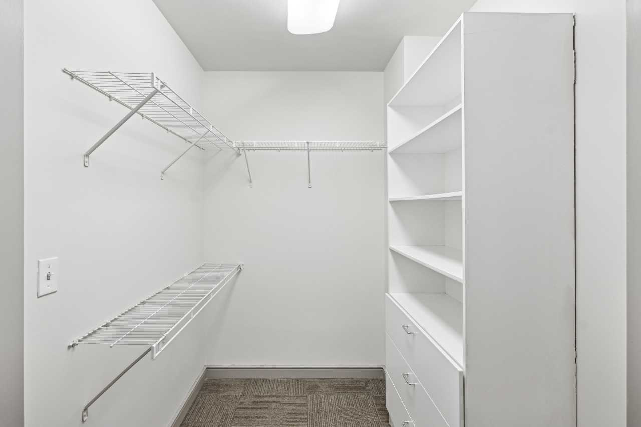 Spacious, all white walk-in closet with hanging space, shelf space and drawers in an apartment at The Continental in Dallas, Texas