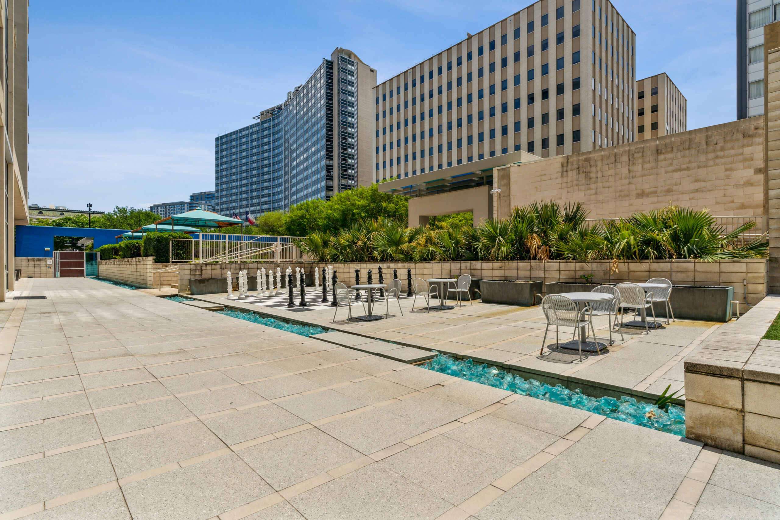 Outdoor pool deck with a stream of pool water running behind outdoor seating tables at The Element apartments in Dallas Texas