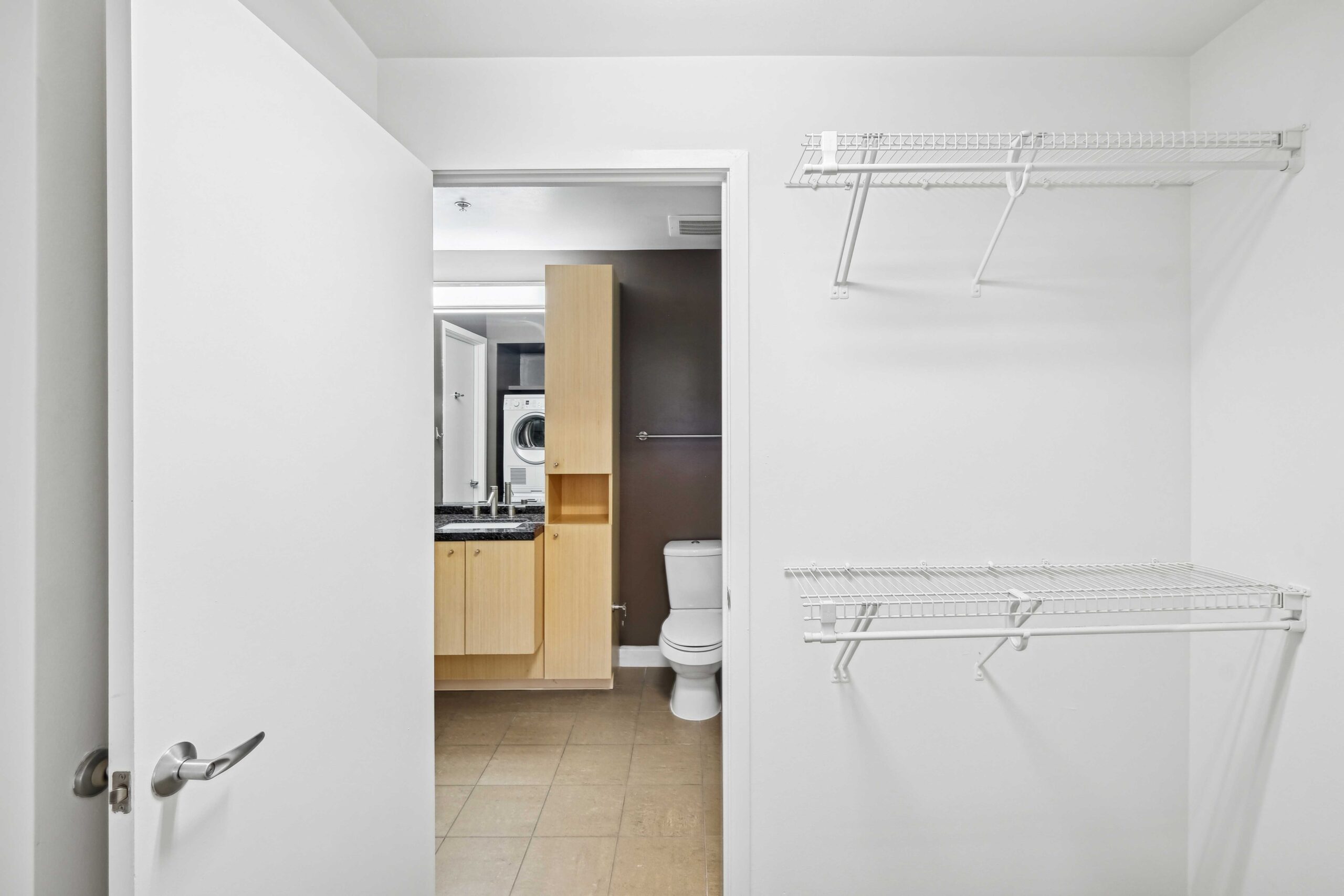 All white walk-in closet with storage space leading to the bathroom in The Elements luxury apartments in Dallas