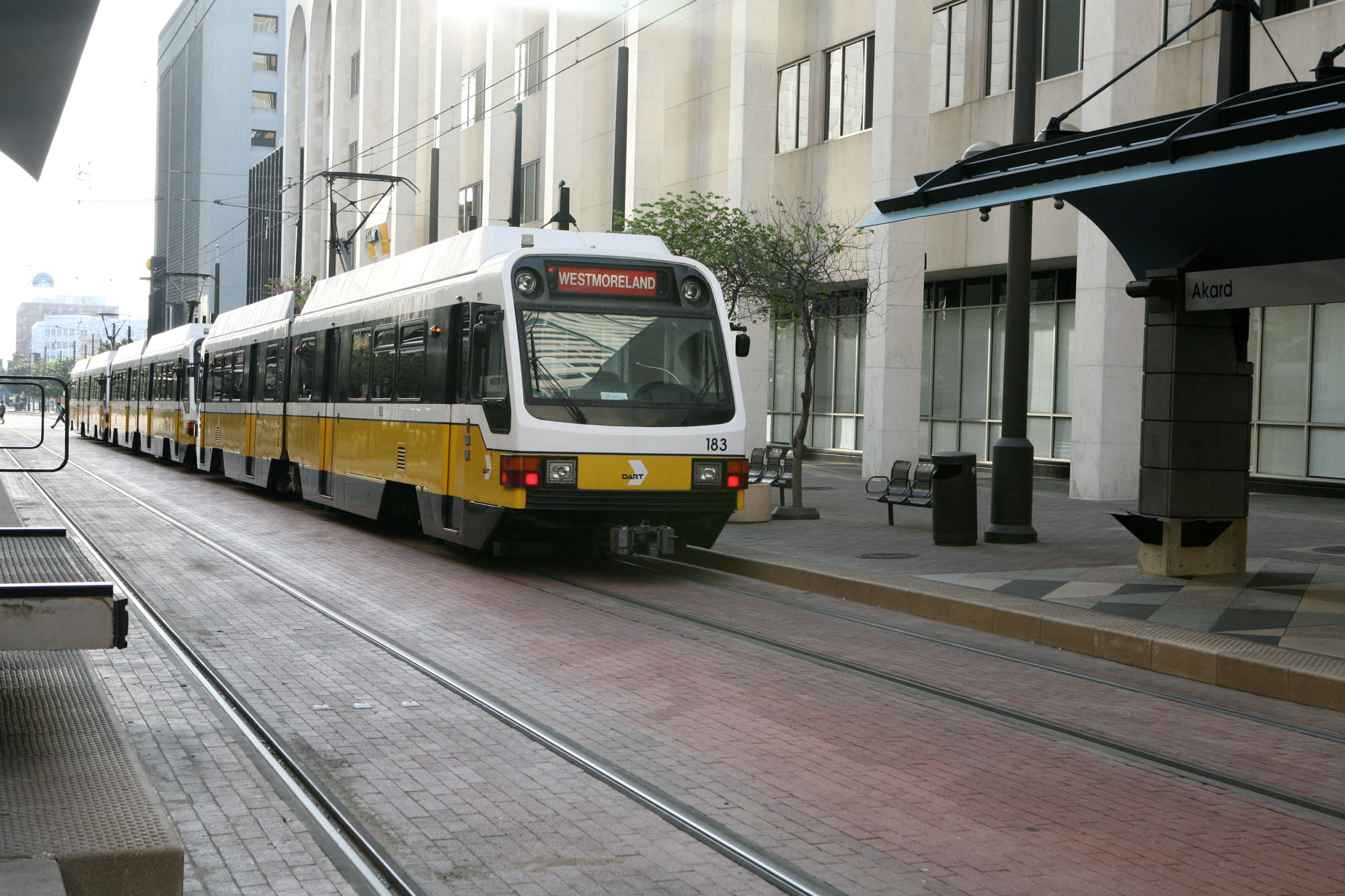 A light train pulling into a station near The Elements luxury apartments in Dallas Texas