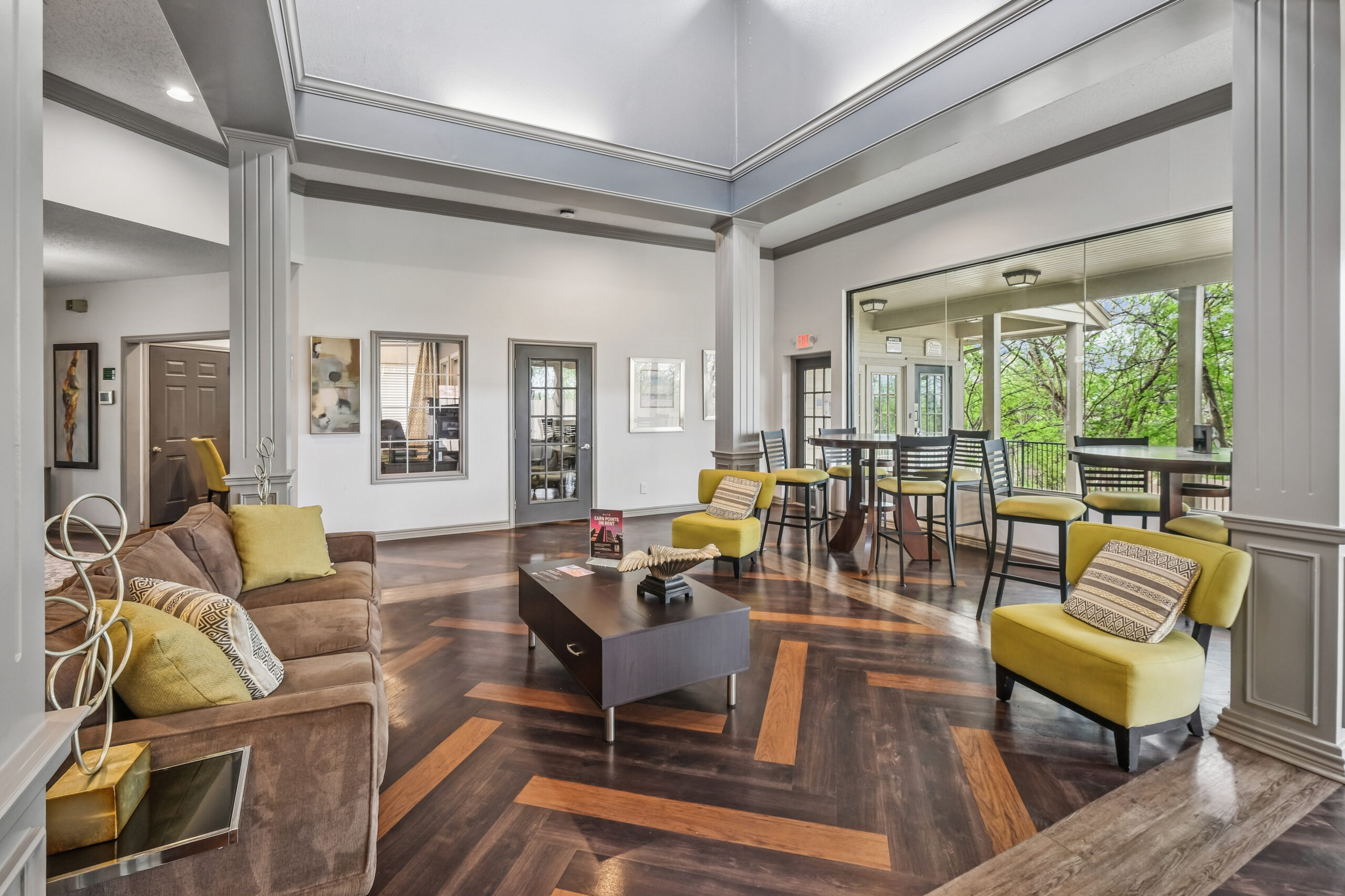 Modern clubhouse at the Gables of Mckinney apartments in Mckinney Texas featuring stylish seating areas, wood flooring, and large windows with natural light.