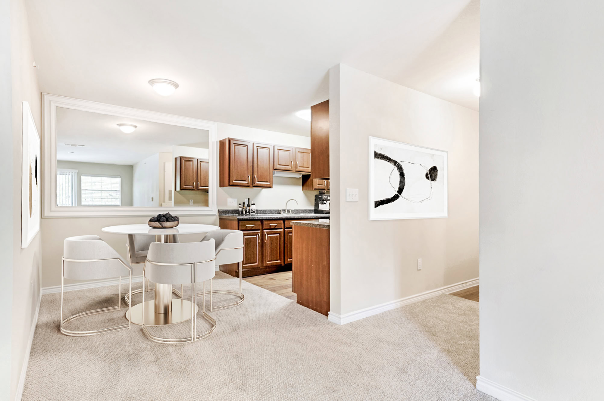 Bright dining area in a Mckinney Texas apartments featuring carpeted flooring, modern seating, and open access to a kitchen with dark wood cabinetry.
