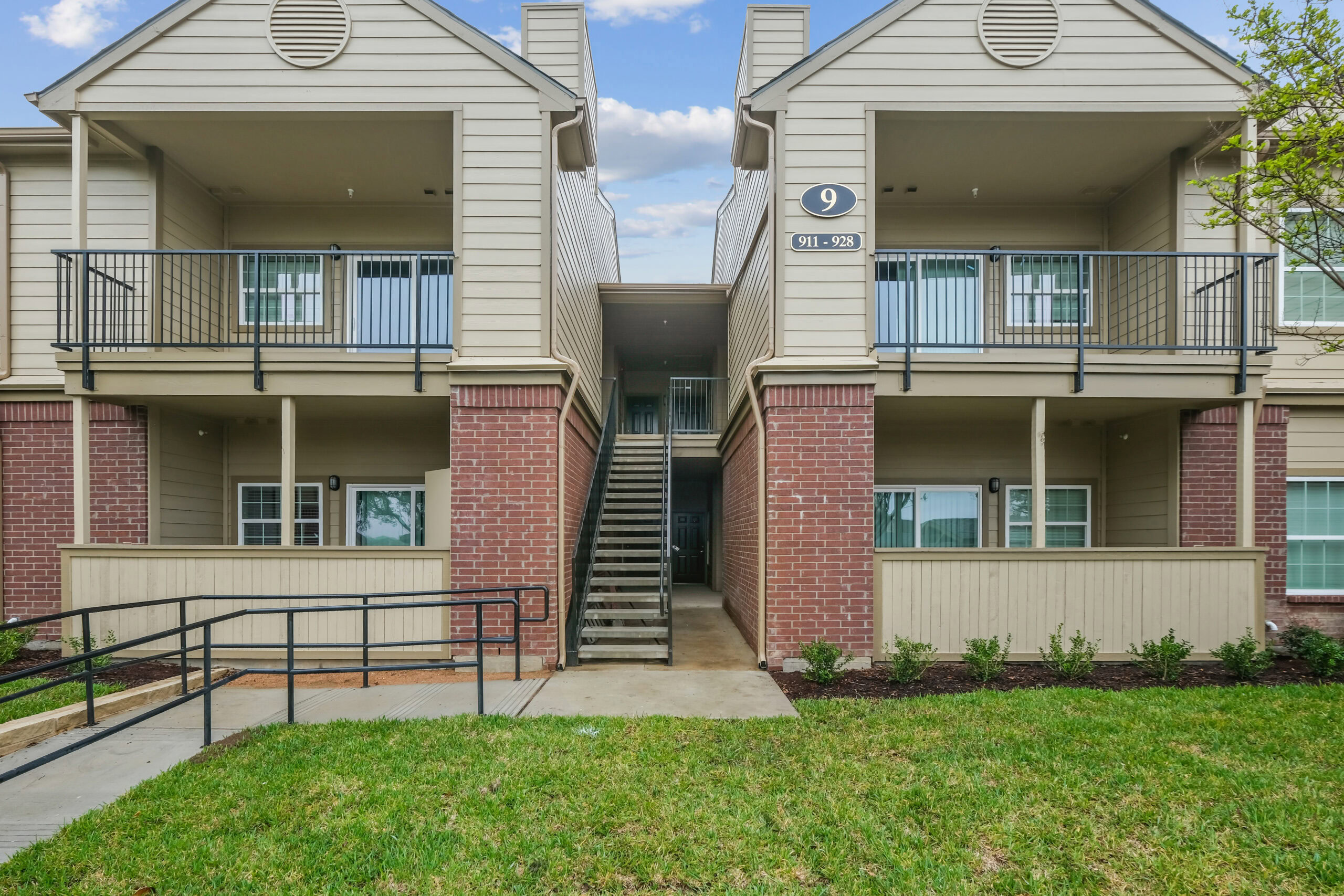 Exterior view of the Gables of Mckinney apartments in Mckinney Texas featuring private patios, balconies, brick accents, and well-maintained landscaping.