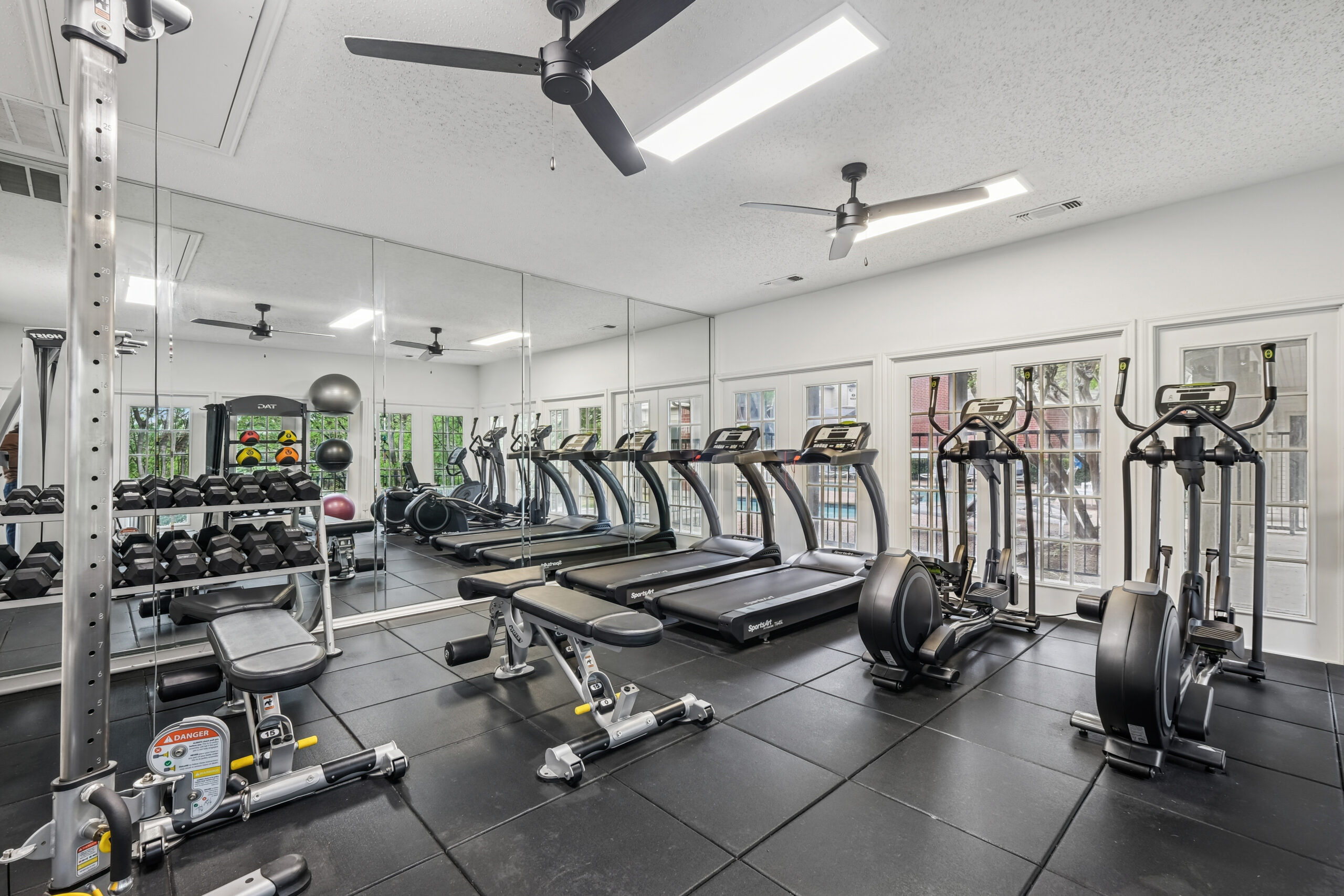 Apartment fitness center the Gables of Mckinney apartments with treadmills, ellipticals, weight bench, dumbbells and a mirror wall