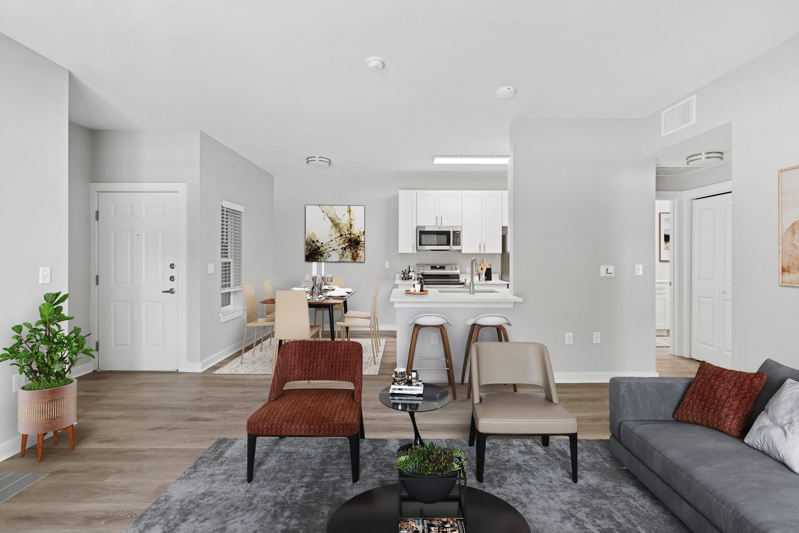 Open-concept living and dining area in a Mckinney Texas apartment featuring modern furniture, white kitchen cabinetry, and wood-style flooring.