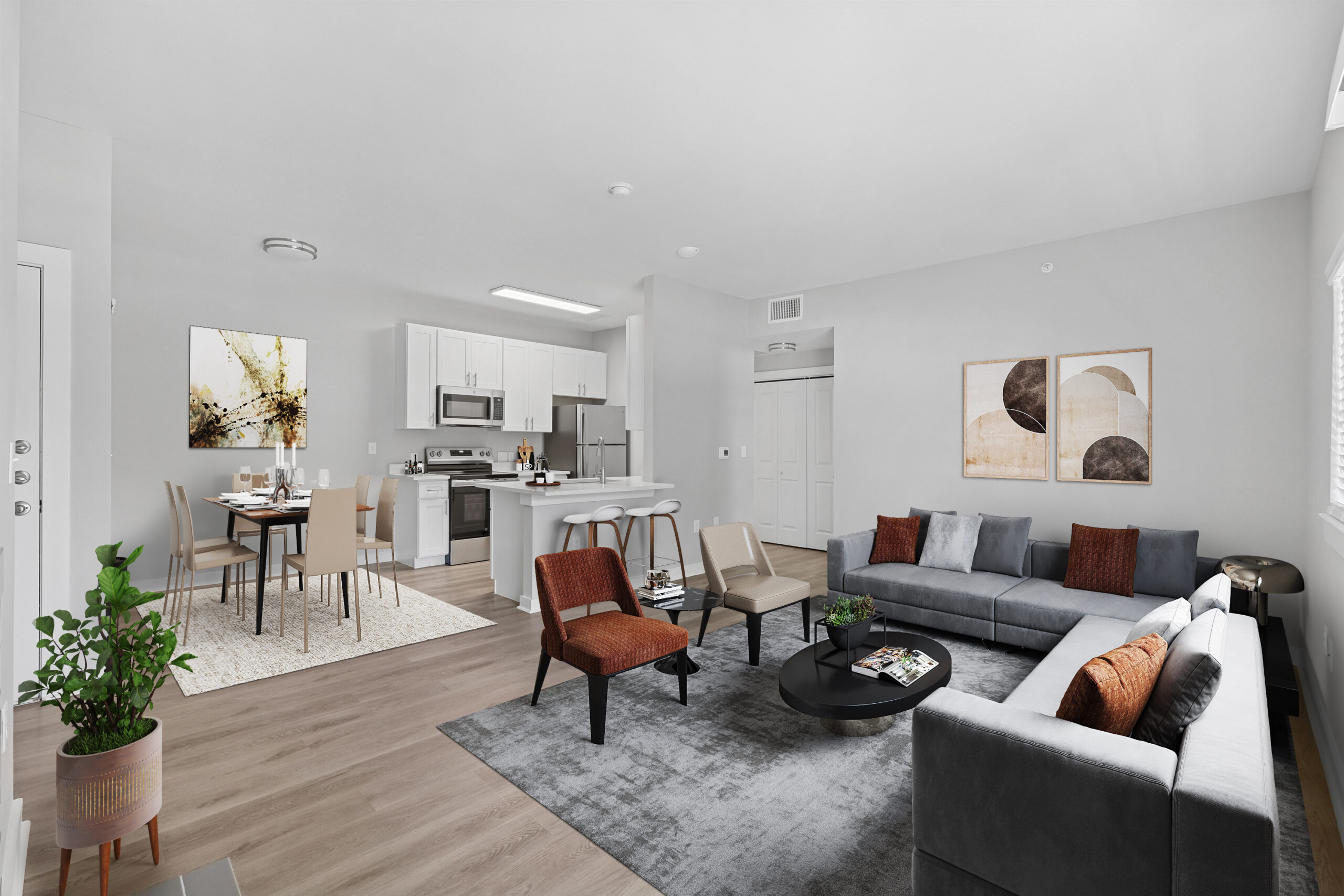 Open-concept living and dining area in a Mckinney Texas apartment featuring modern furniture, a dining space, white kitchen cabinetry, and wood flooring.