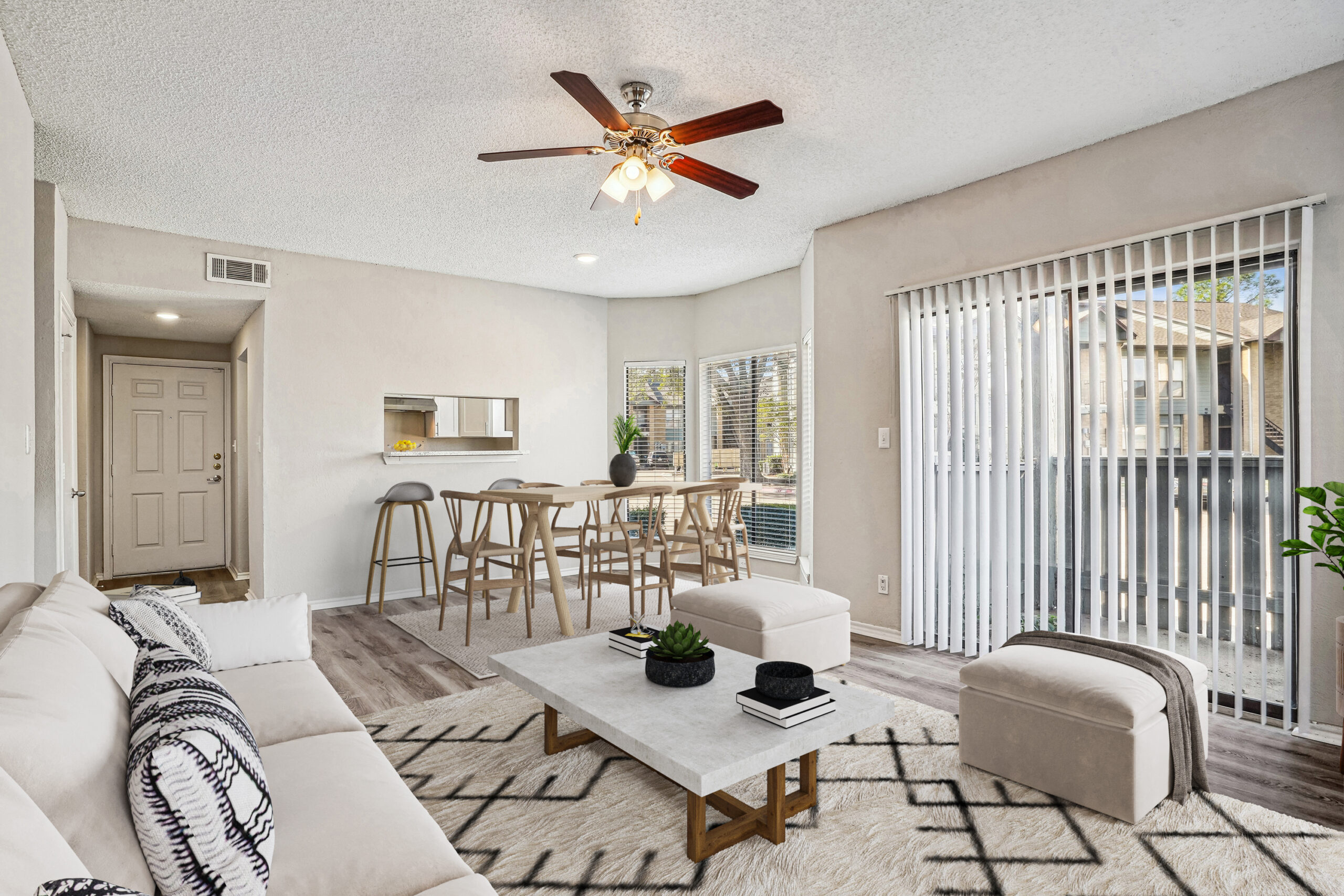 Bright living and dining area in apartments in Garland Texas, featuring wood-style floors, sliding balcony doors, and modern furniture