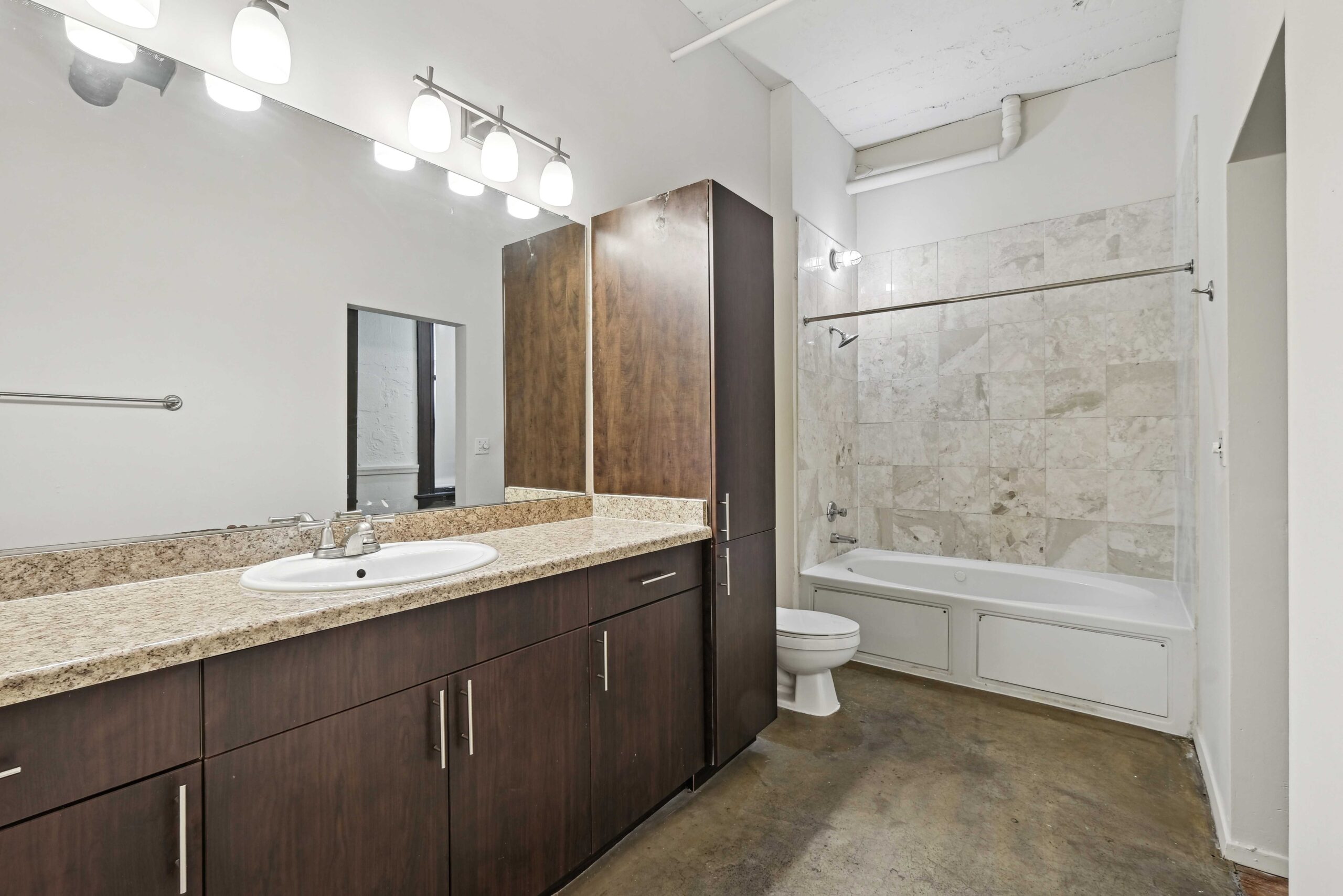 A bathroom with a two sink vanity, tub and shower in an apartment at The Wilson in Dallas, Texas