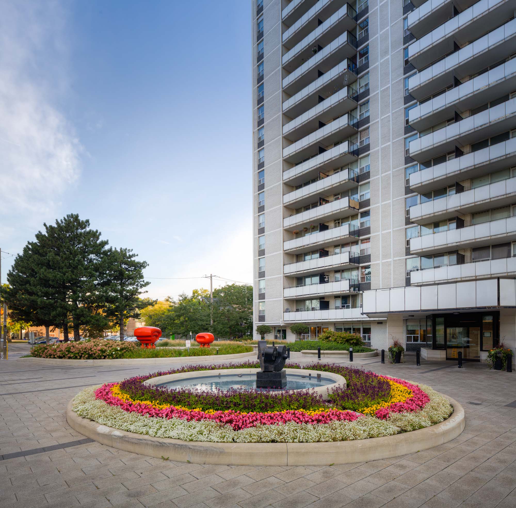 A water feature surrounded by a flower garden in front of the 77 Davisville Toronto apartments