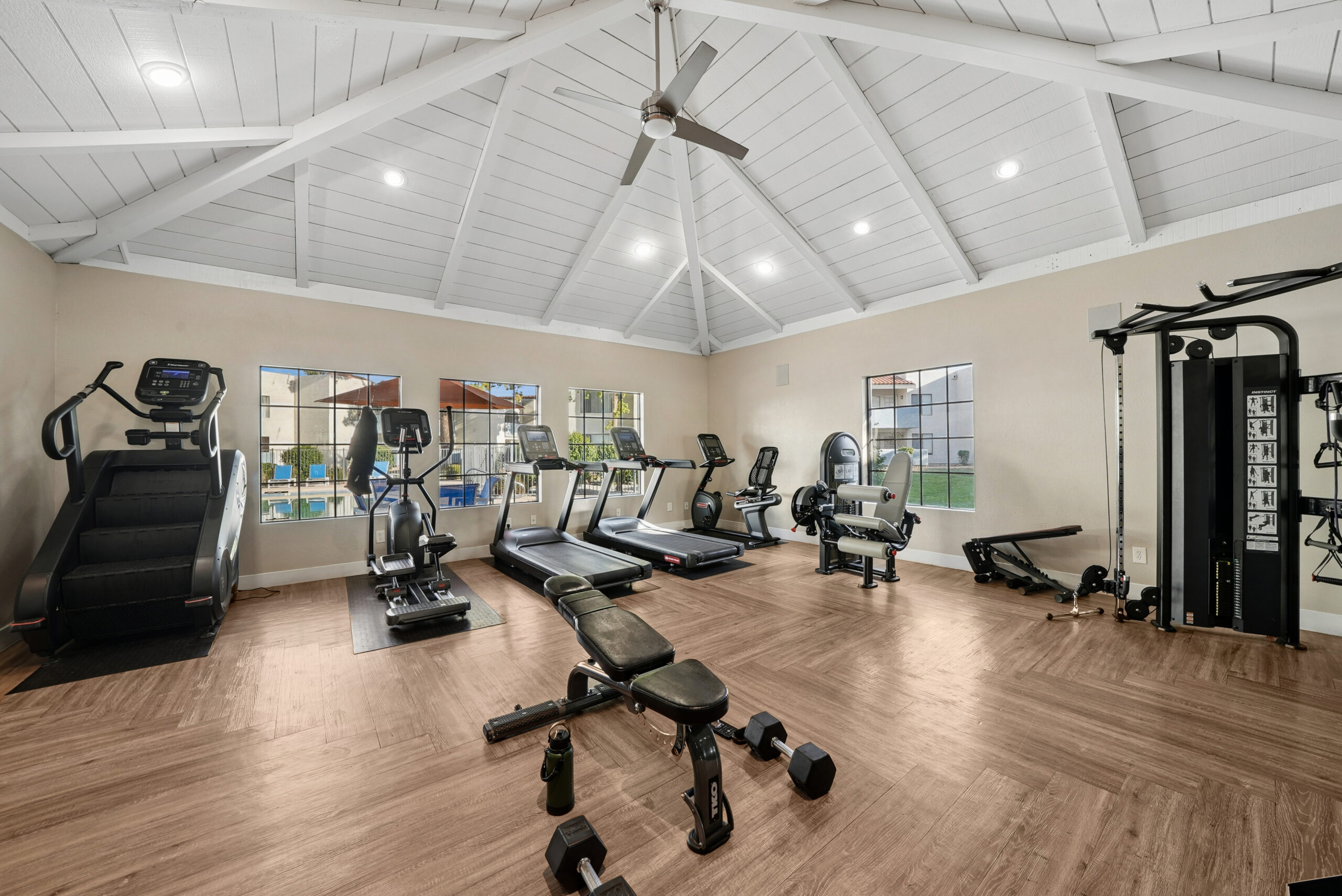 Community fitness center with treadmills, cardio machines, strength-training equipment, free weights, and vaulted ceilings.