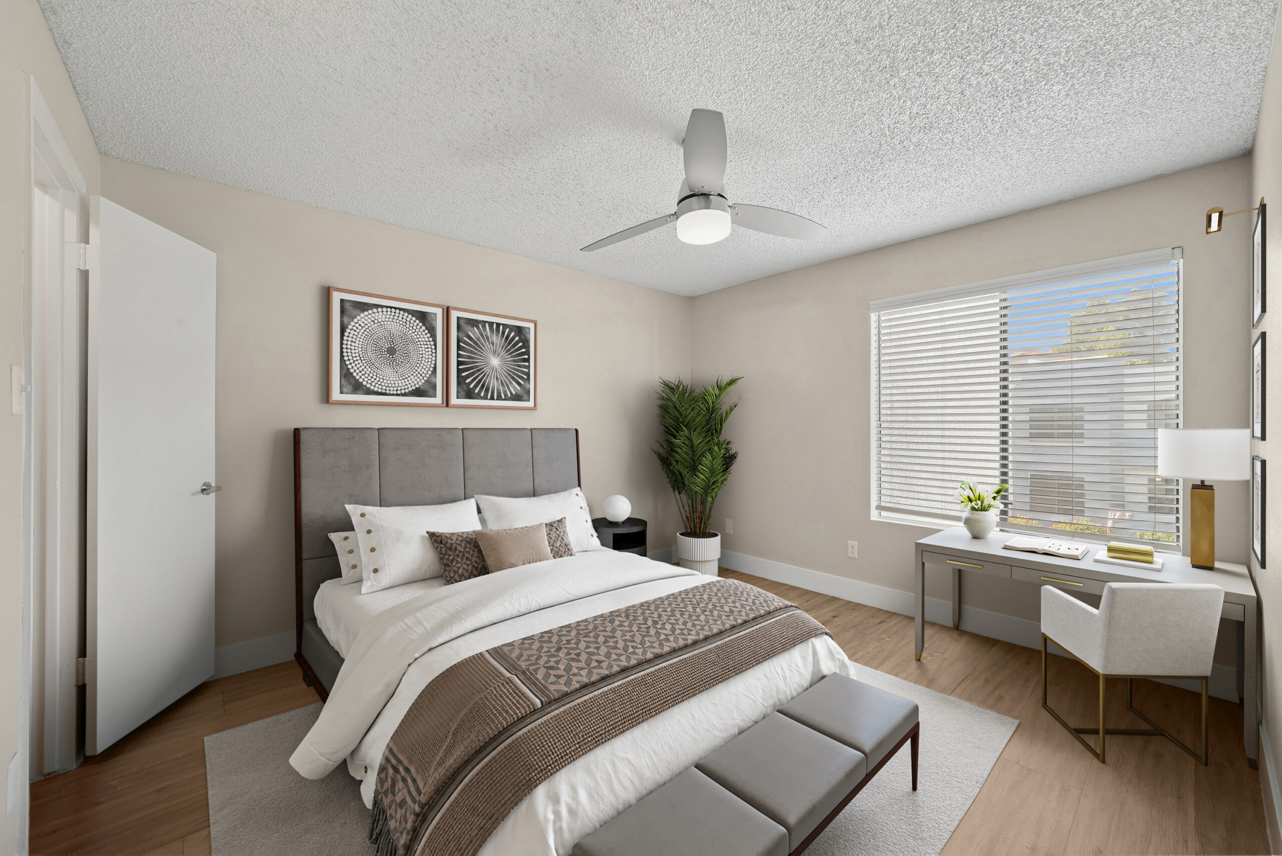 Bright bedroom at Arches at Hidden Creek featuring wood-style flooring, a ceiling fan, large window and dedicated workspace.